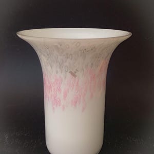 May include: A white glass vase with a flared top. The vase has a pattern of pink and gray swirls and dots near the top. The bottom of the vase is solid white.