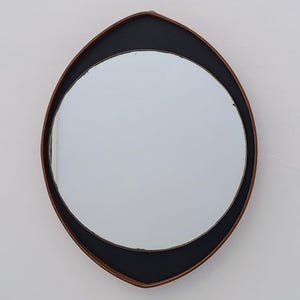 以下が含まれることがあります： ユニークな形の装飾的な壁掛けミラー。 ミラーは、中央に円形の鏡があり、黒と茶色のフレームが付いています。 フレームは黒と茶色の組み合わせで、印象的なコントラストを生み出しています。 ミラーは壁に取り付けるように設計されています。