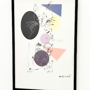 Könnte beinhalten: Gerahmter Kunstdruck mit einer stilisierten Katzenillustration mit geometrischen Formen in Schwarz, Gelb, Rosa und Blau. Die Katze ist in Schwarzweiß gehalten, mit dem Namen "Sam" und der Signatur des Künstlers.