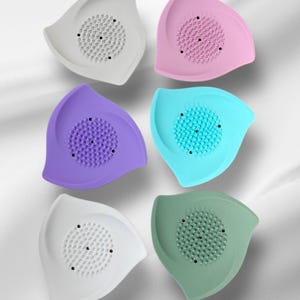 May include: A collection of six colorful silicone face scrubbers. Each scrubber is leaf-shaped with a textured center for exfoliation. Colors include white, pink, purple, teal, and green.