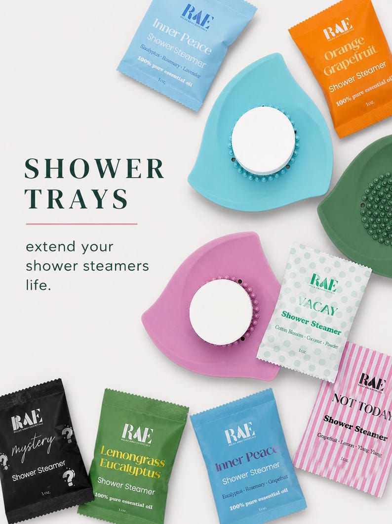 May include: An overhead shot displays shower trays and shower steamers. The trays are in various colors, including blue, green, and pink. The shower steamers come in different scents, such as "Inner Peace" and "Orange Grapefruit."