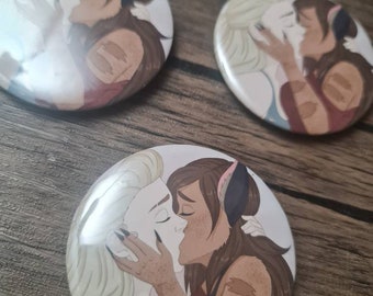 May include: Three circular pin-back buttons featuring a colorful illustration of two characters kissing. One character has blonde hair and light skin, while the other has brown hair, cat-like ears, and brown skin with darker markings on the arms.