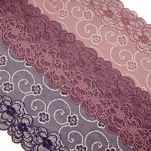 Può includere: Un primo piano di un bordo di pizzo viola e rosa con un motivo floreale. Il pizzo è delicato e intricato, con un bordo smerlato.