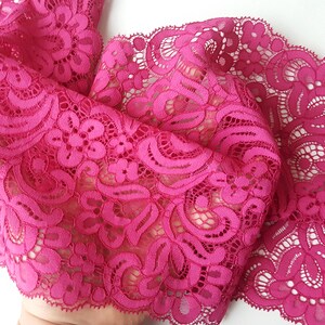 May include: Pink lace trim with a delicate floral pattern. The lace has a scalloped edge.