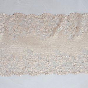 May include: Beige lace trim with a floral pattern. The lace has a scalloped edge.