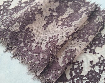 May include: A close-up of a delicate, brown lace trim with a scalloped edge. The lace has a floral pattern and is made of a sheer fabric.