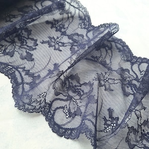 May include: Navy blue lace trim with a floral pattern. The lace is delicate and has a scalloped edge.