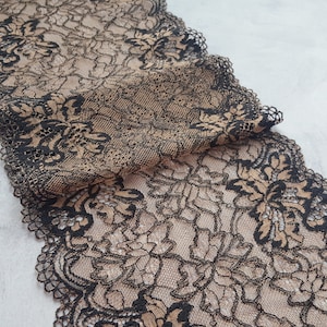 May include: Black and beige lace trim with a floral pattern. The lace is delicate and intricate, with a scalloped edge.