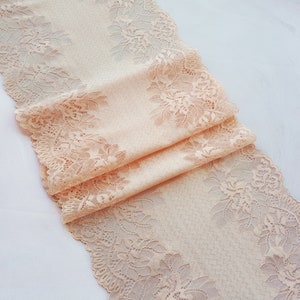 May include: Peach colored lace trim with a floral pattern. The lace is folded in thirds and has a delicate, intricate design.