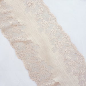 May include: Beige lace trim with a delicate floral pattern. The lace is soft and has a slightly textured surface.