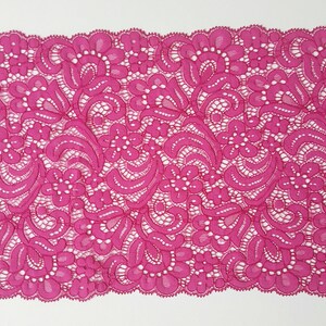 May include: Pink floral lace trim with a delicate pattern. The lace is soft and has a scalloped edge.