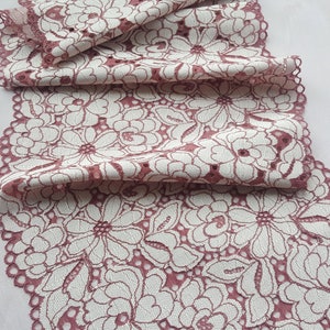 May include: Pink lace trim with a white floral pattern. The lace is delicate and has a scalloped edge.