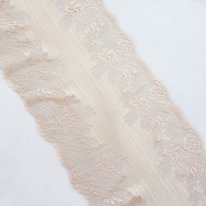 May include: Beige lace trim with a delicate floral pattern. The lace is soft and has a slightly textured surface.