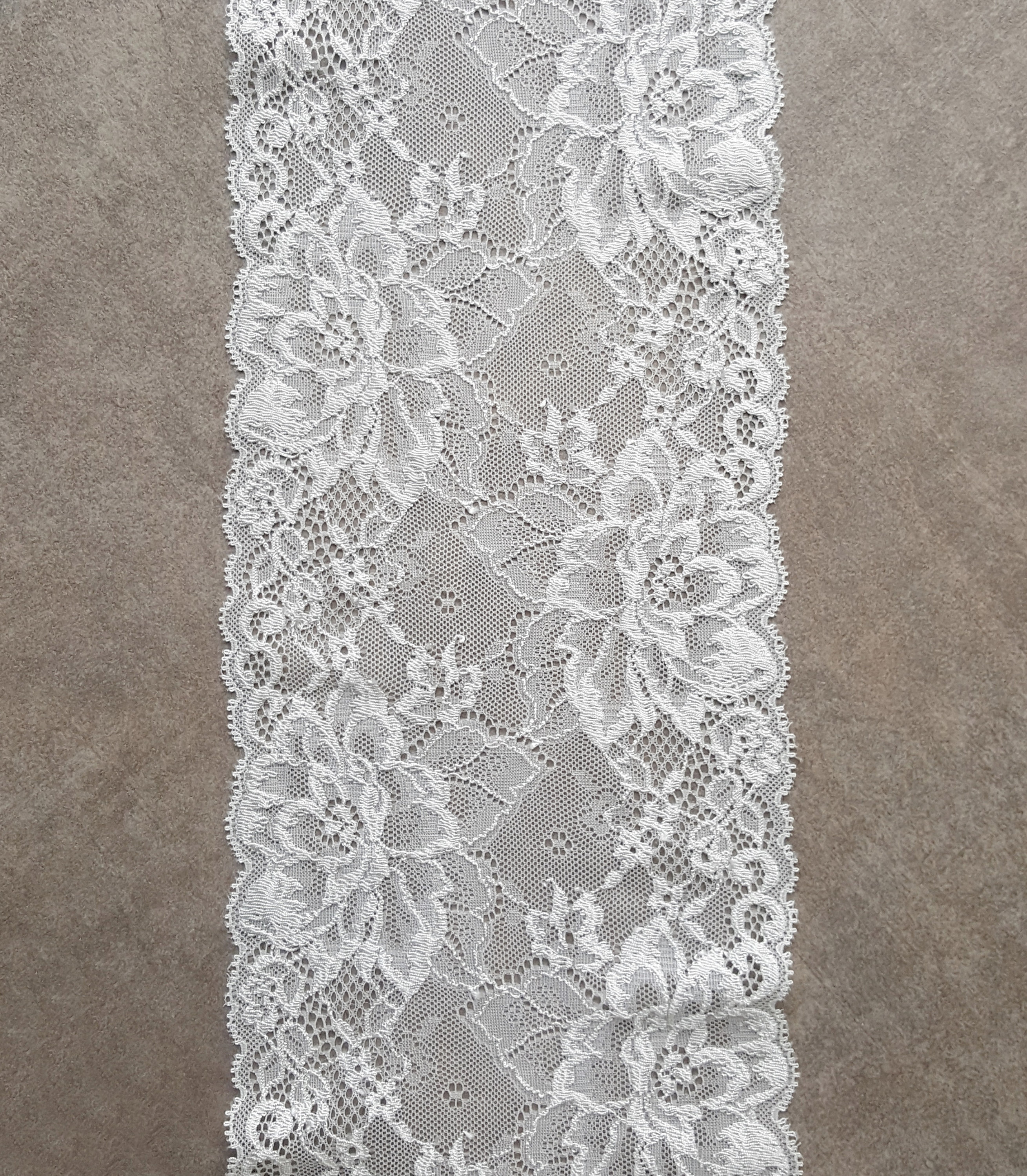 May include: White lace trim with a floral pattern. The lace is delicate and intricate, with a scalloped edge.