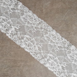 May include: White lace trim with a floral pattern. The lace is delicate and intricate, with a soft, flowing texture.