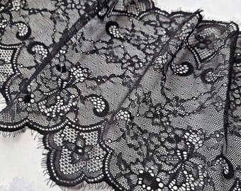 May include: Black lace trim featuring a delicate floral design. The lace has a scalloped edge and is ideal for adding a touch of elegance to any project.