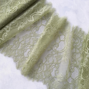 Könnte beinhalten: Salbeigrüne Spitzenborte mit zartem Blumenmuster. Die Spitze hat einen gewellten Rand und ist weich und durchsichtig.