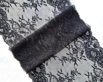 May include: Black lace trim with a floral pattern. The lace is delicate and intricate, with a scalloped edge.