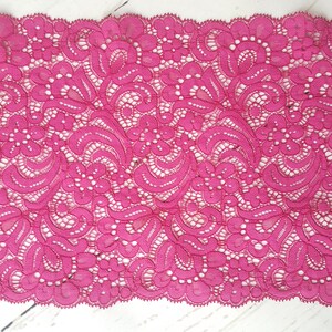 May include: Pink lace trim with a delicate floral pattern. The lace has a scalloped edge.