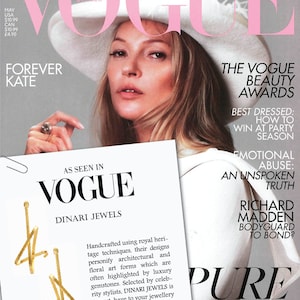 May include: A magazine cover featuring a woman wearing a white hat with a feather. The magazine is titled "Vogue" and features the text "The Vogue Beauty Awards" and "Best Dressed: How to Win at Party Season".