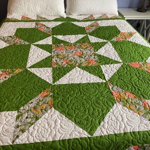 May include: A green and white quilt with a starburst pattern. The quilt is made with a floral fabric and a solid green fabric.