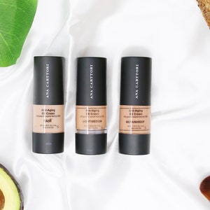 Op de afbeelding: Drie flessen Ana Carttori Anti-Aging BB Cream in de tinten Licht, Licht/Medium en Medium/Donker.