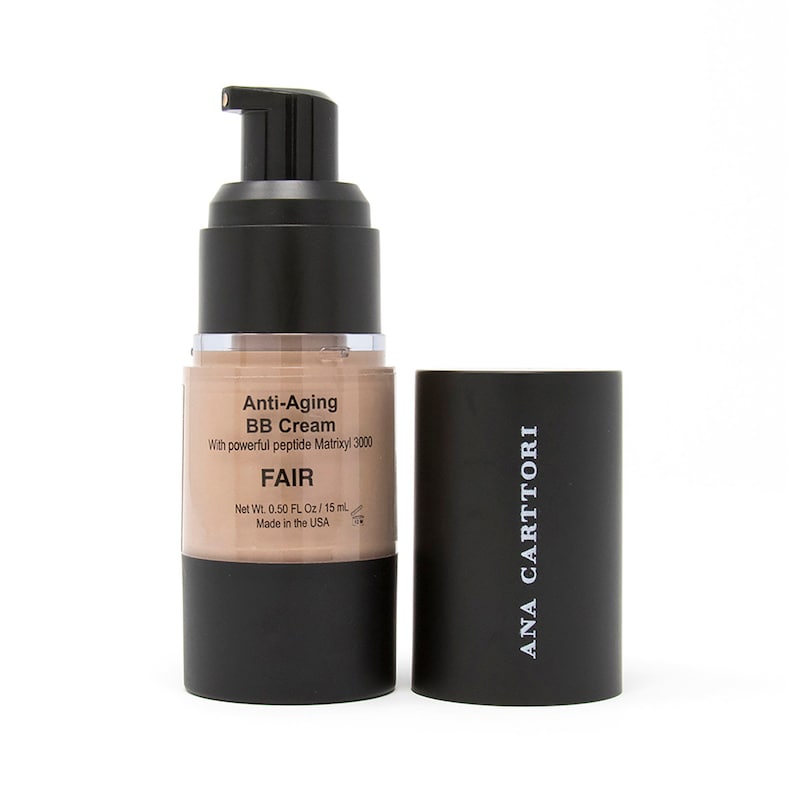 Op de afbeelding: Een zwarte en transparante pompflacon met Ana Carttori Anti-Aging BB Cream in de kleur Fair. De flacon is voorzien van een etiket met de productnaam, ingredi&euml;nten en het nettogewicht van 0,50 fl oz / 15 ml. De flacon is gemaakt in de VS.