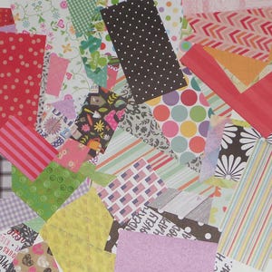 May include: A collection of patterned scrapbook paper in various colors and designs, including polka dots, stripes, arrows, and floral patterns.