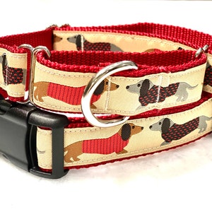 May include: Red and beige dog collar with a black buckle and silver D-ring. The collar features a repeating pattern of dachshunds wearing red sweaters.