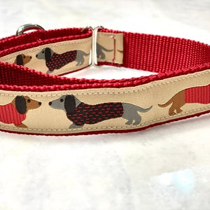 May include: Red and beige dog collar with a pattern of dachshunds wearing red sweaters.