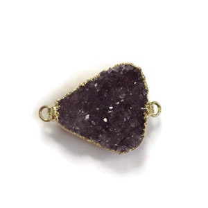 May include: A purple amethyst crystal pendant with a gold-toned metal frame and two loops for attaching to a necklace or bracelet.