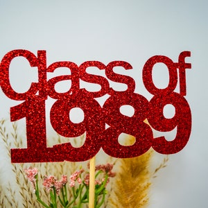 May include: Red glitter Class of 1989 cake topper. The topper is made of red glitter cardstock and is perfect for a graduation party.