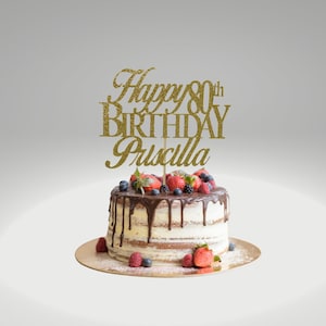 May include: Gold glitter cake topper with the text "Happy 80th Birthday Priscilla" on a cake decorated with chocolate frosting and fresh berries.