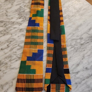 May include: Two neckties with a colorful geometric pattern in shades of yellow, green, blue, red, and black. The ties are made of woven fabric and have a pointed tip.