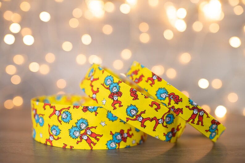 May include: Three yellow fabric headbands with a repeating pattern of red and blue figures from the book "The Cat in the Hat".