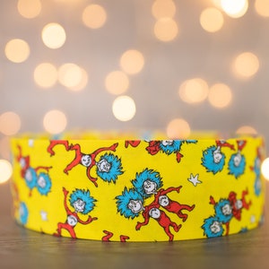 May include: Yellow fabric with a repeating pattern of the characters from the book "The Cat in the Hat".