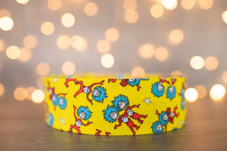 May include: Yellow fabric with a repeating pattern of the characters from the book "The Cat in the Hat".