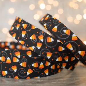 Può includere: Nastro in tessuto nero e arancione con un motivo a mais dolce e glitter argentato. Il nastro è arrotolato e ha un tema di Halloween festivo.