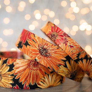 Peut inclure: Trois rouleaux de ruban à motifs floraux orange et rouge sur un fond blanc avec des lumières dorées floues.