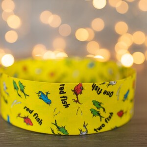 May include: A yellow cardboard tube with a colorful pattern of fish and the words "one fish, two fish, red fish, blue fish".