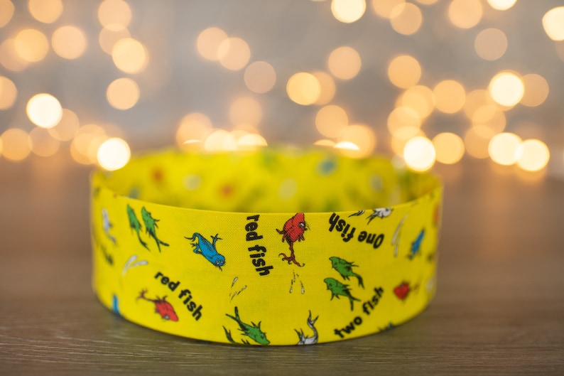 May include: A yellow cardboard tube with a colorful pattern of fish and the words "one fish, two fish, red fish, blue fish".