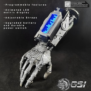 Puede incluir: Un brazo robótico plateado y negro con una pantalla de matriz LED animada. Cuenta con funciones programables, correas ajustables y una batería mejorada. El texto de la imagen dice: "Funciones programables", "Pantalla de matriz LED animada", "Correas ajustables".