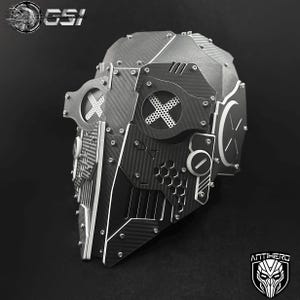 May include: A futuristic, silver and black helmet with carbon fiber accents and riveted metal plates. The helmet features an X-shaped design on the visor and side panels, with the word "ANTIHERO" and a logo at the bottom.