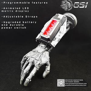 Puede incluir: Un brazo robótico plateado con una pantalla de matriz LED roja y correas ajustables. El brazo cuenta con una batería mejorada y un interruptor de encendido duradero. El texto en la imagen enumera las características programables y la marca "GSI".