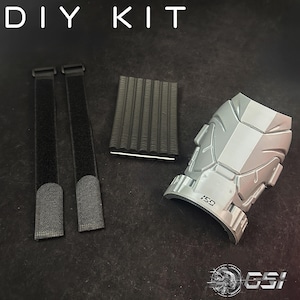 Puede incluir: Un kit de bricolaje con el texto "DIY KIT" en la parte superior. El kit incluye dos correas de velcro negras, una almohadilla de espuma negra y un protector de brazo de plástico gris con el texto "GSI" impreso. El protector de brazo tiene un diseño geométrico.