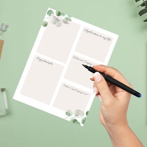 Op de afbeelding: Een witte journaalpagina met prompts voor reflectie, waaronder "Today's Voice" en "Application to my life". De pagina is versierd met aquarel eucalyptusbladeren en wordt beschreven met een zwarte pen. De achtergrond is lichtgroen.