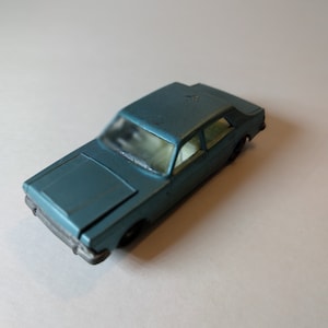 May include: A blue toy car model with a white interior. The car is a sedan with a closed roof and four doors.