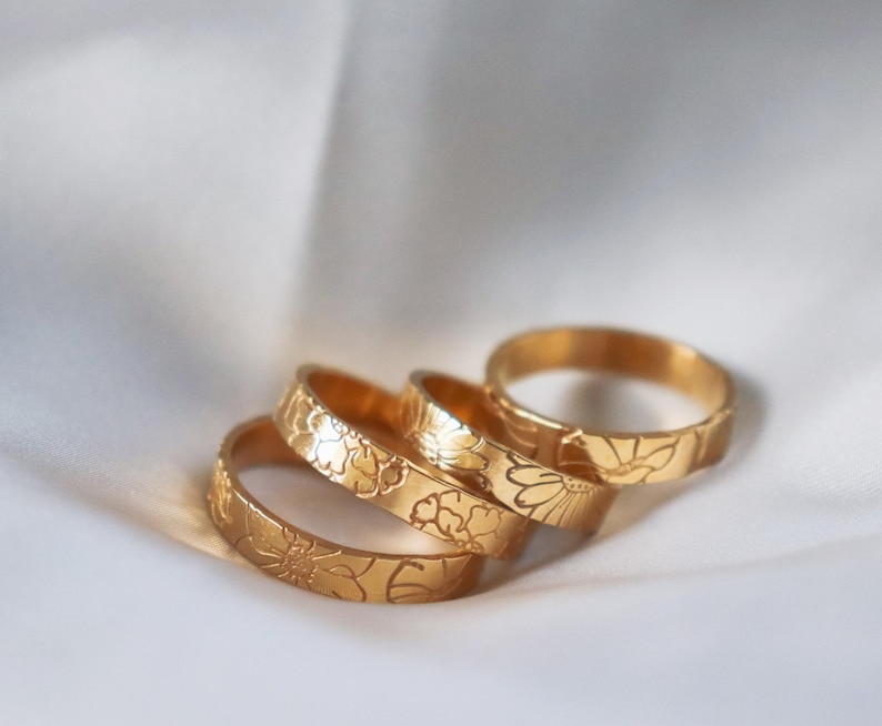 Op de afbeelding: Drie gouden ringen met een bloemenmotief. De ringen zijn op elkaar gestapeld.