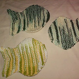 May include: Three knitted dishcloths in the shape of fish. The dishcloths are green, white, and yellow.