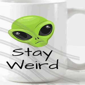 May include: White ceramic mug with a green alien face and the text "Stay Weird" printed on it.